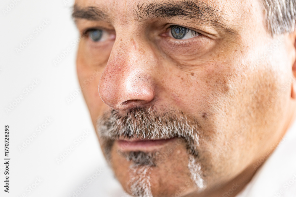 Obraz premium Close-up portrait of a mature man with a calm, neutral expression, focusing on the details of his face.