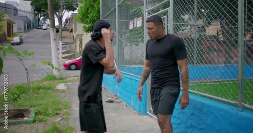 Two Hispanic men outdoors in tense confrontation escalating into argument and physical altercation, intense emotions, anger, conflict, street tension, raw human drama and aggression