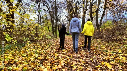 Mother with two children walking in autumn park