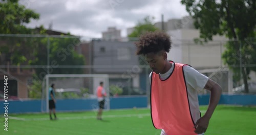 Close up of Brazilian man of African descent juggling soccer ball on green field demonstrating balance, agility and confidence during solo training practice outdoors