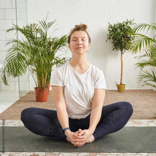 Foto Caucasian young adult female meditating in yoga pose at indoor studio with green plants