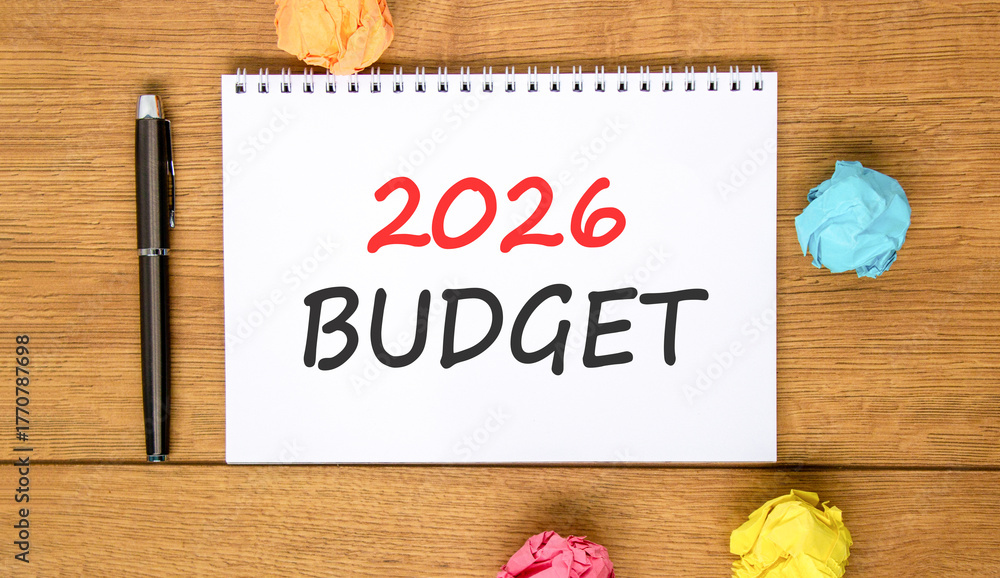 Fototapeta premium 2026 Budget symbol. Concept words 2026 Budget on beautiful white note. Beautiful wooden background. Black pen. Colored paper. Business and 2026 budget concept. Copy space.