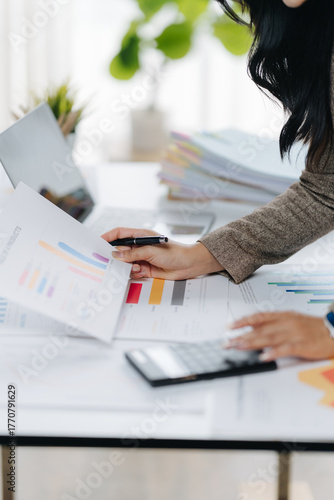 Analyzing Financial Reports: Focused hands meticulously review financial reports, accompanied by a calculator and stacks of documents, showcasing diligent attention to detail.