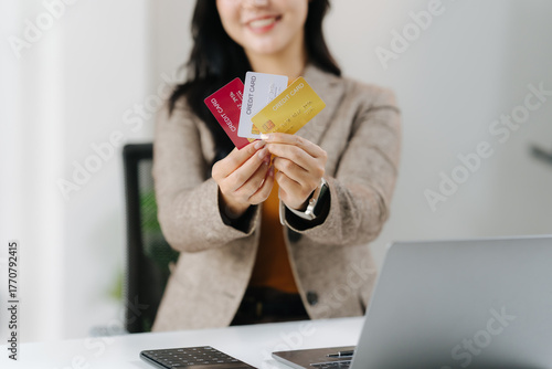 Payment Options: A professional businesswoman holds a selection of credit cards, showcasing diverse payment options in a modern business setting, while presenting a welcoming and friendly demeanor.