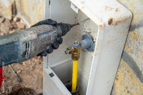 The main connection point for the natural gas line on the building's exterior. Inside the box is a yellow natural gas pipe (PE pipe), a brass valve connected to it, and a connection assembly.