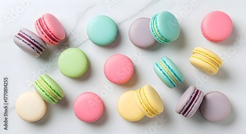 A delightful assortment of pastel-colored French macarons in pink, green, yellow, purple, and cream, artfully scattered on a marble surface for a chic and elegant dessert display.

