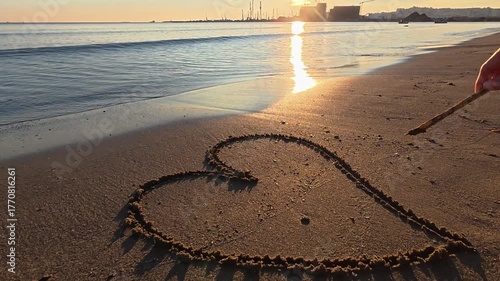 Heart shape drawn on sandy beach near the sea. Romantic seaside scene symbolizing love, affection, and peaceful summer mood.