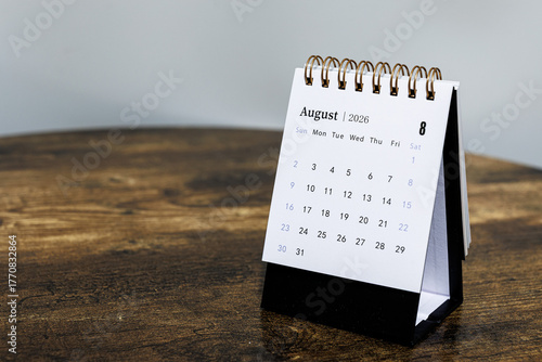 August 2026 monthly calendar page on a wooden desk, minimal design planner representing time management and organization at workplace