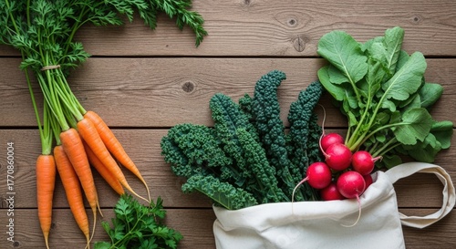 Fresh vegetables including orange carrots, green kale, and red radishes arranged on a wooden surface. A white bag holds some of the greens.
