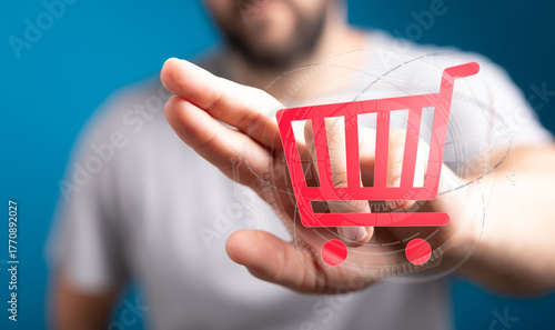 A man's hand holds a shopping cart symbol, conveying online shopping, e-commerce, and digital retail concepts. Represents purchasing power and t