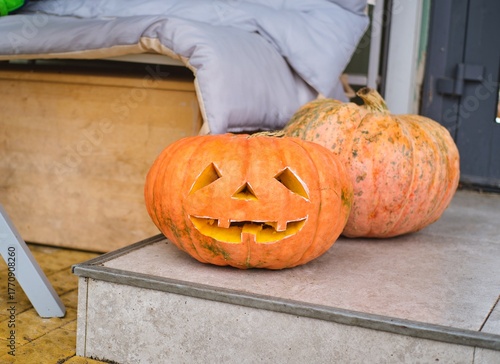 A carved Jack-o'-lantern on the street outside a cafe. Happy Halloween.
