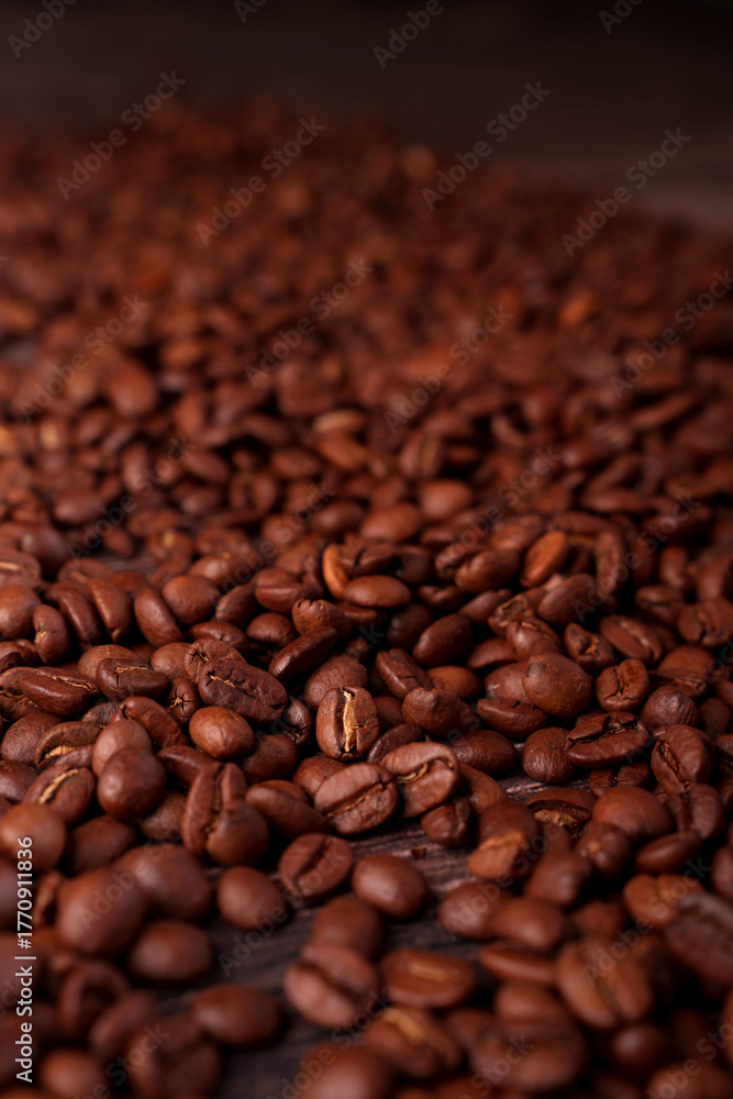 Fototapeta premium close-up view of a rich pile of roasted coffee beans showcasing their glossy texture and deep brown hues, evoking the aroma and warmth of freshly brewed coffee in an inviting ambiance, unroasted