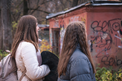 Photography Woman and girl, possibly mother and daughter, stand near a graffiti-covered buil