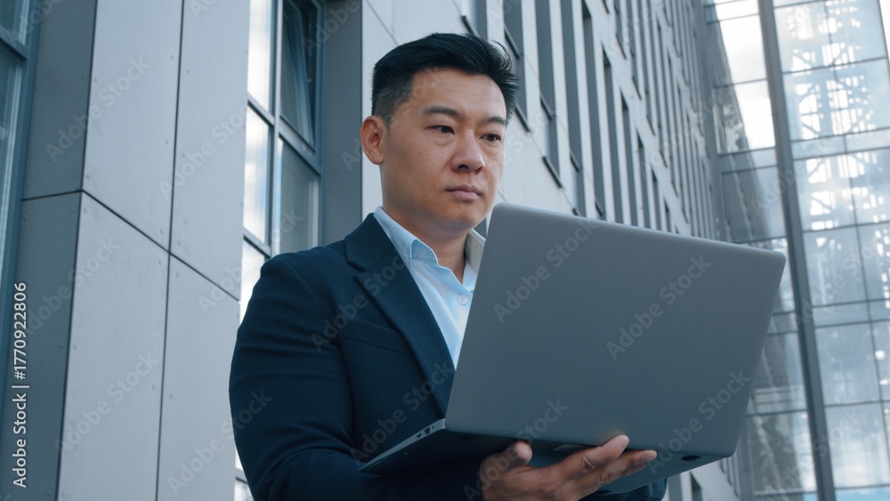 Fototapeta premium Asian business man Korean middle-aged businessman with laptop in city male Japanese employer concentrated Chinese manager typing wireless portable computer working chatting remote distant job online