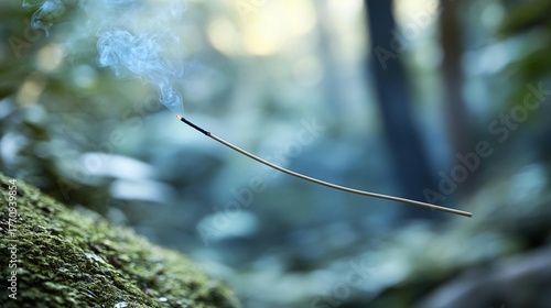 Serene moment with burning incense stick producing delicate smoke in a lush natural green