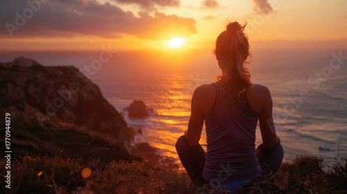 Woman meditating on cliff during sunset over ocean