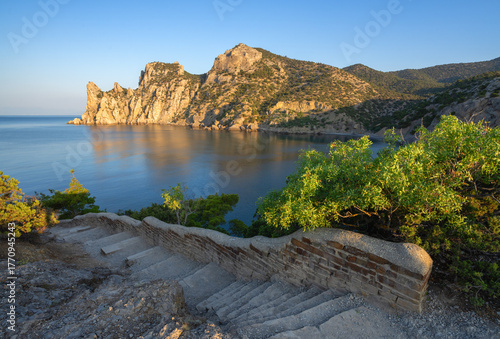 Stone path among mountains and greenery overlooking the calm bay of Novy Svet, Crimea