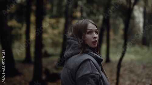 Frightened woman turning around and running through dark forest