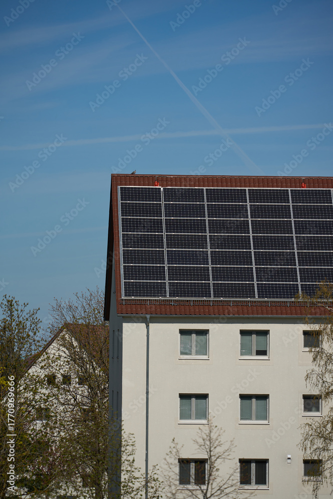 Fototapeta premium Residential building with solar panels on roof. Multi-story building with solar panels. Energy efficient solution in urban setting.
