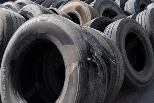 Pile of used car tires ready for recycling. Stacked old tires in a recycling yard. Old worn-out tires piled together outdoors.