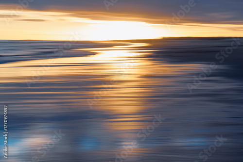 Abstract seascape with blurred golden and blue hues at sunset.