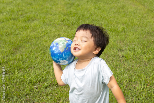 地球儀を持って草原で立っている男の子（2歳、日本人、笑顔）