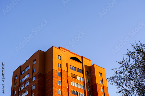 Brick building under clear blue sky during golden hour in a quiet neighborhood