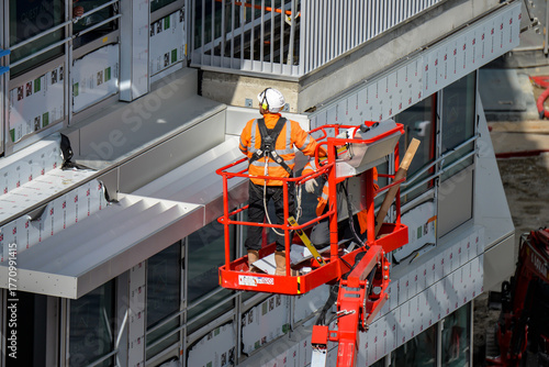 Des ouvriers du bâtiment sur une nacelle installant des matériaux sur l'extérieur d'un immeuble