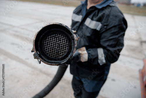 A worker holds an oil sleeve. Close-up of the hose and camlock . Oil field concept, industry and oil and gas production