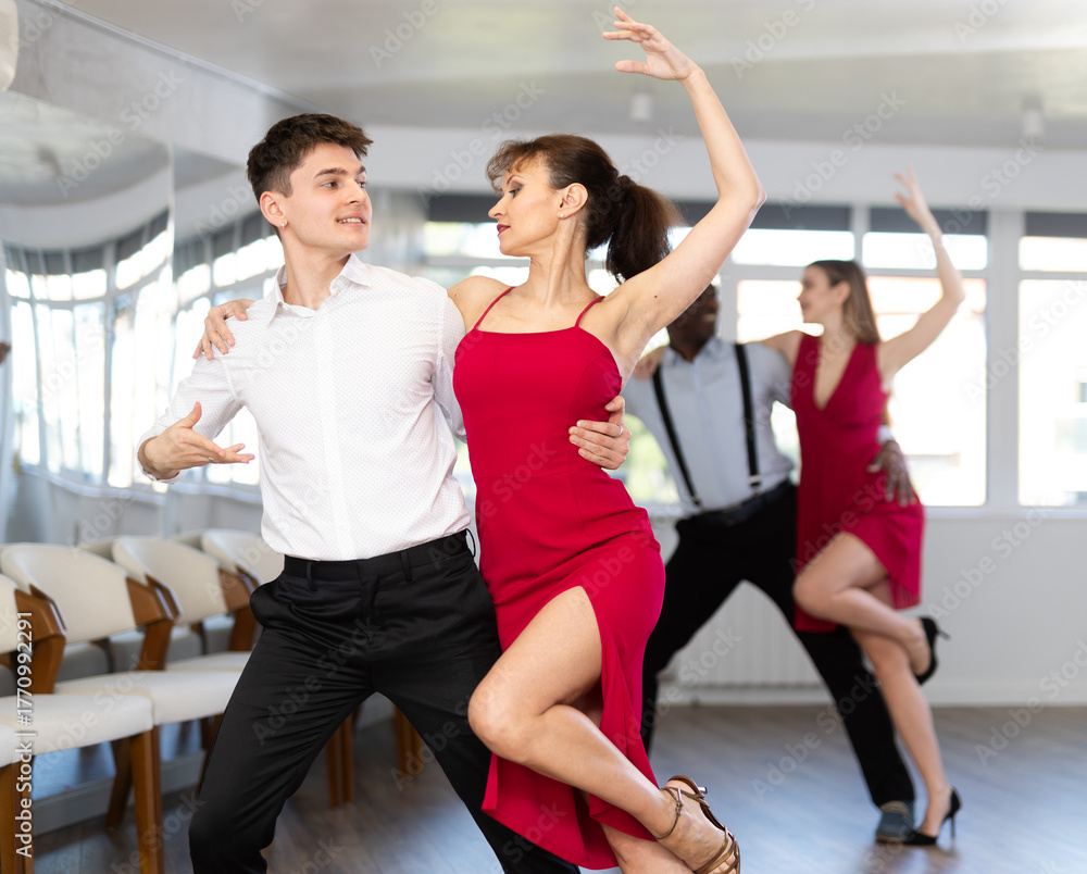Fototapeta premium Couple of young guy and adult woman dancing tango in studio..