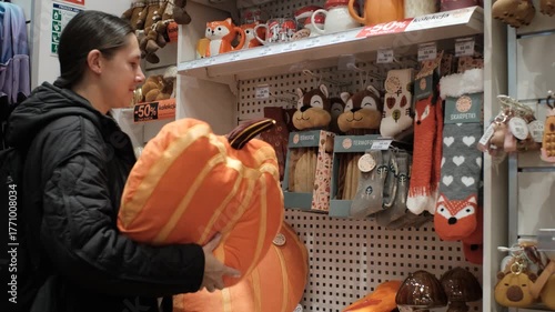 Smiling woman hugging giant plush pumpkin in store