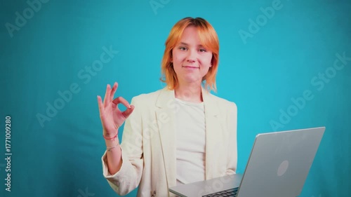 Young businesswoman holding laptop making ok gesture