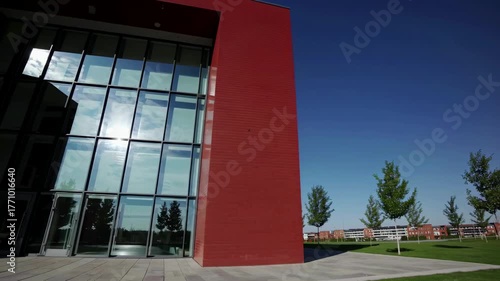 Wide-angle shot of a modern red-brick building under a clear blue sky, capturing its sleek design. Ideal for an architectural video concept.