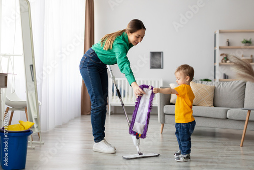 Tableau sur toile A mother and her young son are engaged in cleaning the floor together