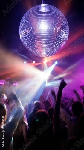 Disco ball illuminating a nightclub with dancing figures and colorful lights