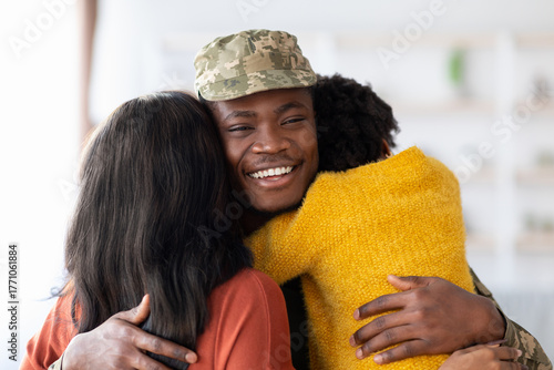 Fotografie A soldier in military uniform is warmly embraced by two family members