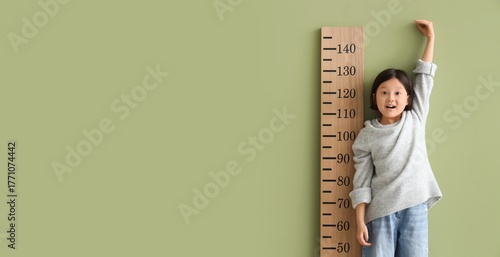 Cute Asian girl measuring h...