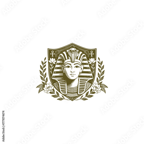 Regal and stylized illustration of an Egyptian Pharaoh's mask (possibly Tutankhamun) centered on a shield, framed by a laurel wreath, sacred lotus flowers, and Egyptian symbols