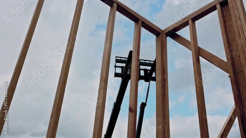 Workers use crane to lift materials at construction site with wooden beams frames