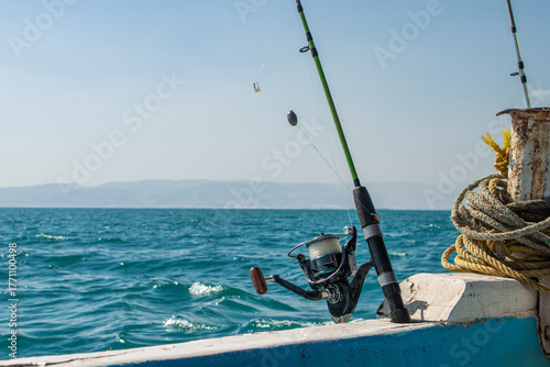 Close up of a fishing rod and reel on a boat with mountain coast