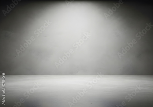 Empty gray studio room with a concrete wall and floor, illuminated by a single spotlight for a minimalist product display background