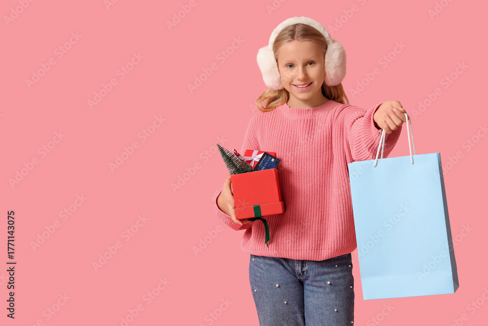 Fototapeta premium Cute girl with shopping bag, gift boxes and credit card on pink background. Christmas celebration