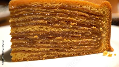Slice of layered caramel cake with a shiny glaze on a white plate