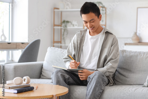 Young Asian man writing som...