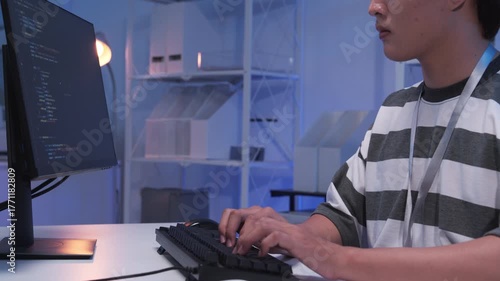 One young male Asian IT freelancer programmer and tech engineer working with computer keyboard, typing software codes for application development and website network system information data in room.