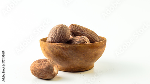Fotografie several piles of nutmeg in a wooden bowl on a white background