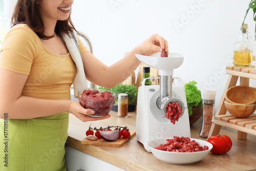 Young housewife using meat ...