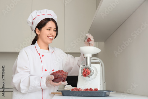 Female chef using meat grin...