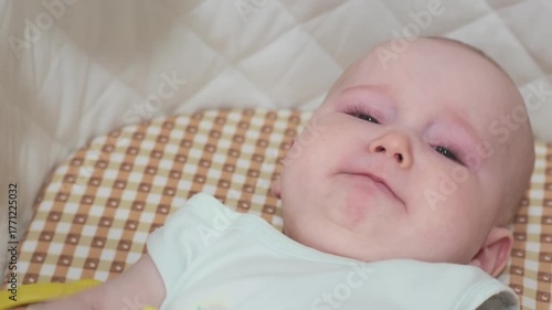  baby girl is lying on the bed and crying. The kid holds her toy.