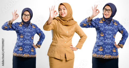 Tableau sur toile Indonesian civil servant women wearing brown and blue batik uniforms showing OK hand gesture with confident smile, symbolizing good performance, professionalism, and government service